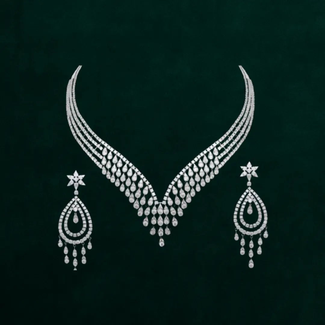 Bridal-ready jewellery set with a V-shaped diamond-look necklace paired with matching tear-drop chandelier earrings, all crafted in premium rhodium-plated alloy for high-shine impact.