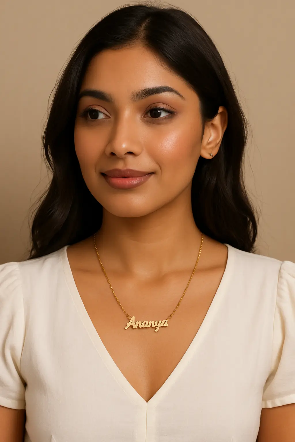 Portrait of a woman wearing a personalized gold name necklace reading "Ananya"